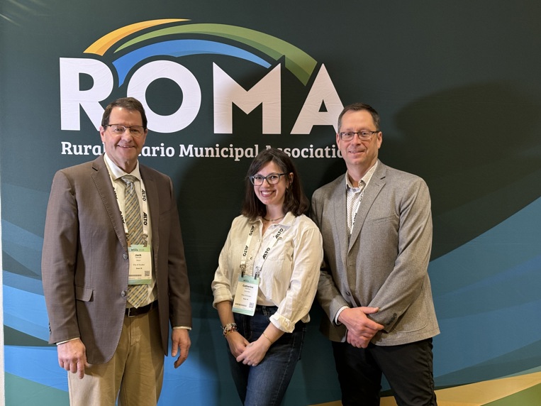 Photo of the mayor, a councillor, and CAO in front of a ROMA backdrop at the 2026 conference in Toronto.